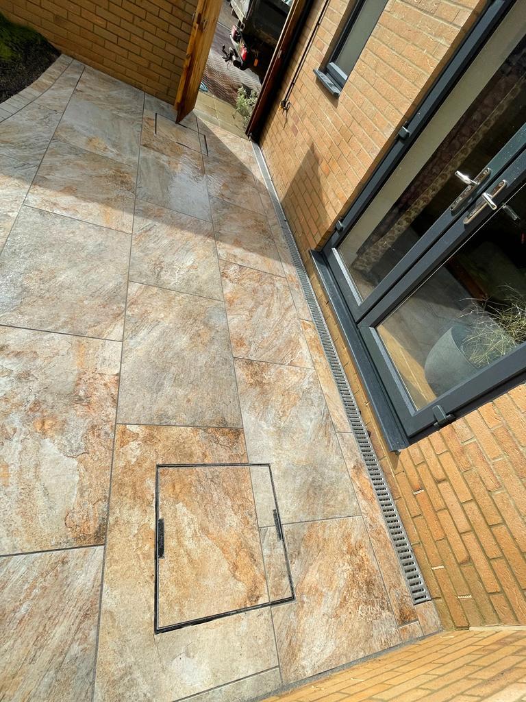 Porcelain paving with linear drainage beside a house